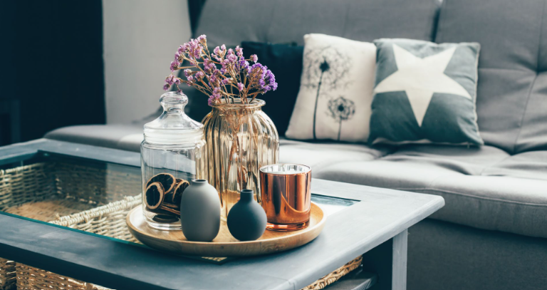 Wohnzimmer mit Sofa, Couchtisch und Tablett mit dekorativen Elementen darauf